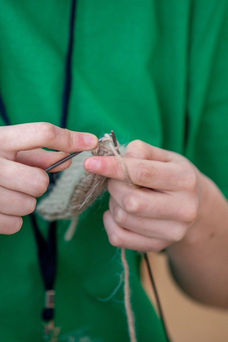 Hands learning to knit with yarn