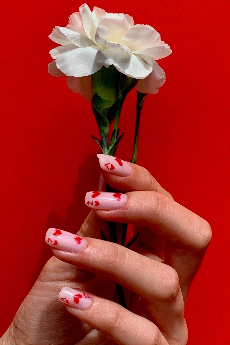 Pink nails covered with small red hearts