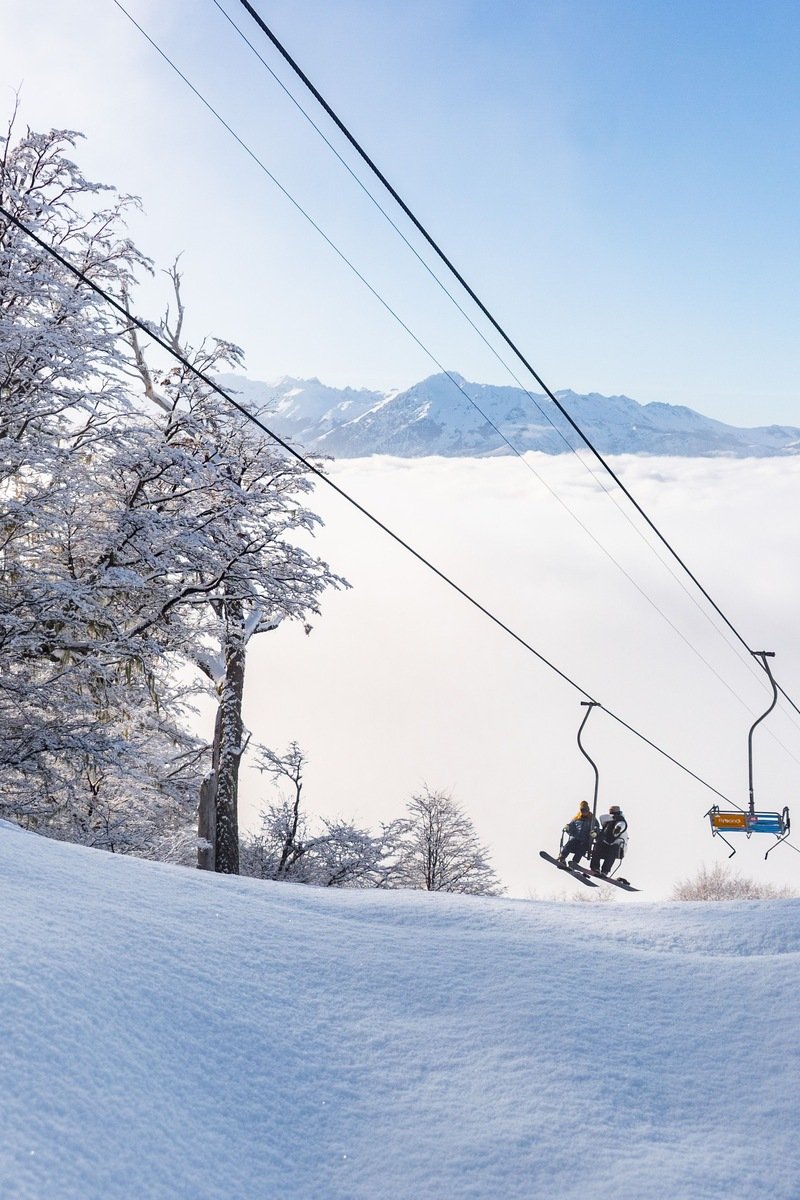 Chairlift carrying skiers over snowy slopes with Cascade peaks in the distance