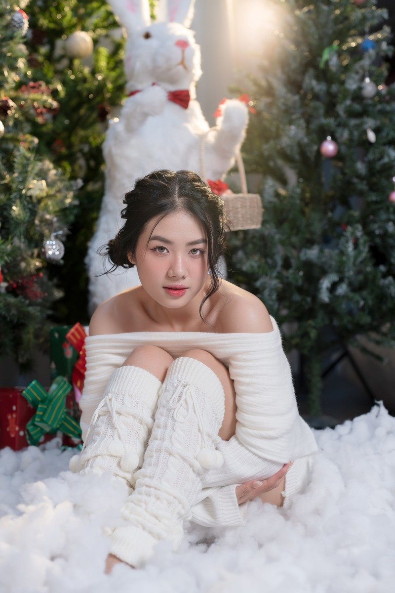 Woman in a white sweater dress and knee-high boots by Christmas decor