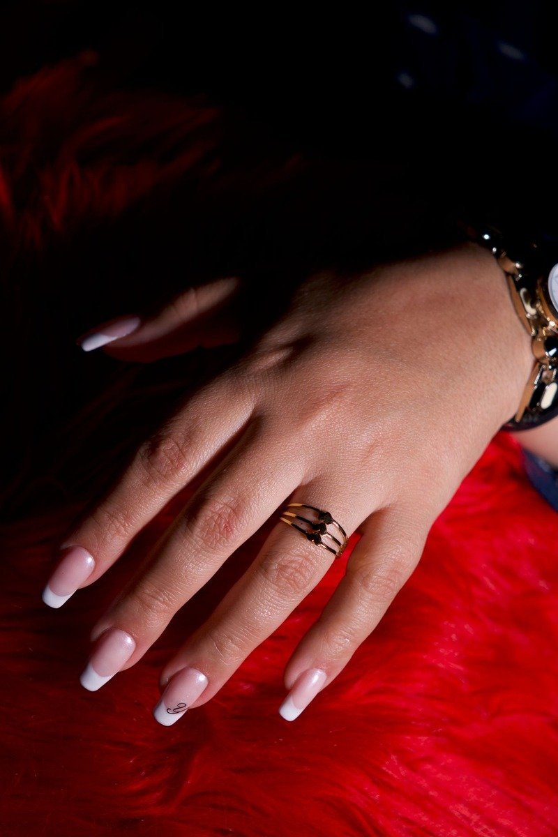 French-tip nails on red faux fur in dark moody lighting