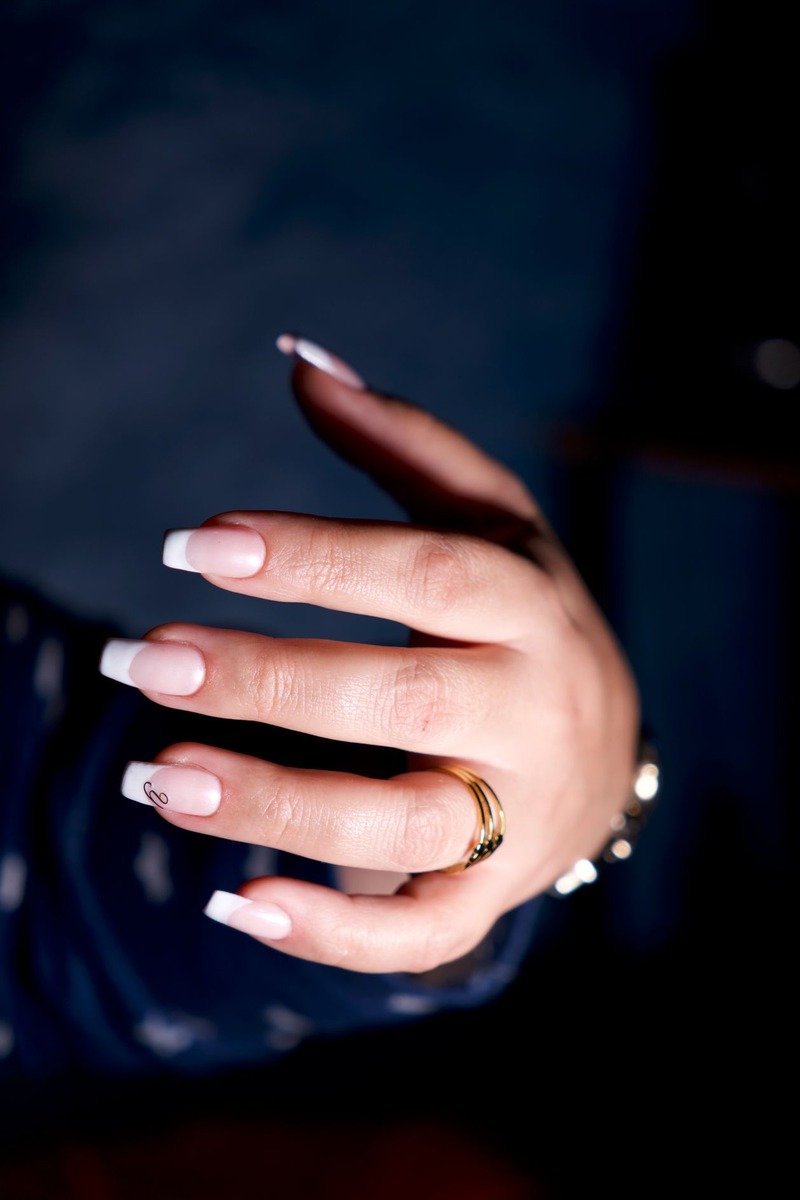 French-tip nails with gold rings on dark blue background