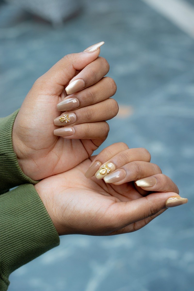 Nude nails with a gold flower accent