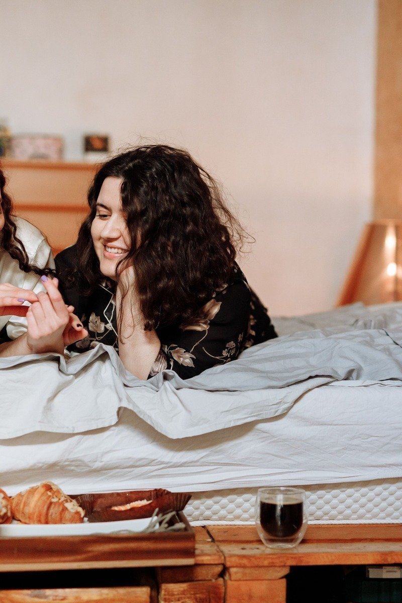 Pajama brunch club with friends in robes enjoying breakfast spread in bed