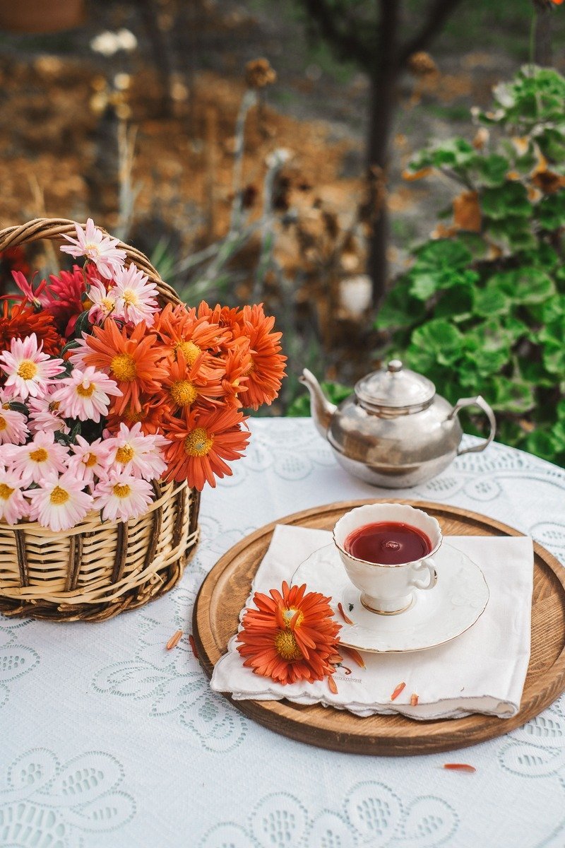 Garden tea party with tiered trays, teapots, and flowers on outdoor table