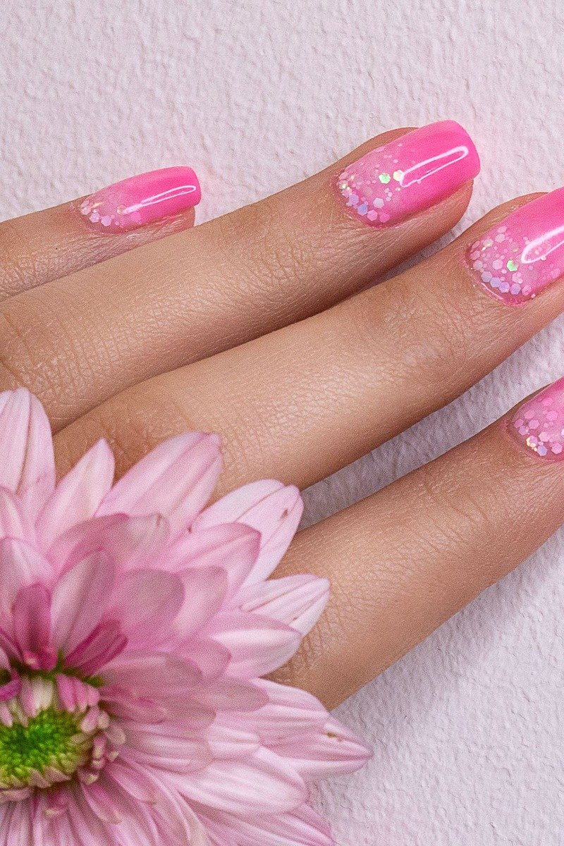 Hot pink nails with glitter dot accents near the tips, pink flower