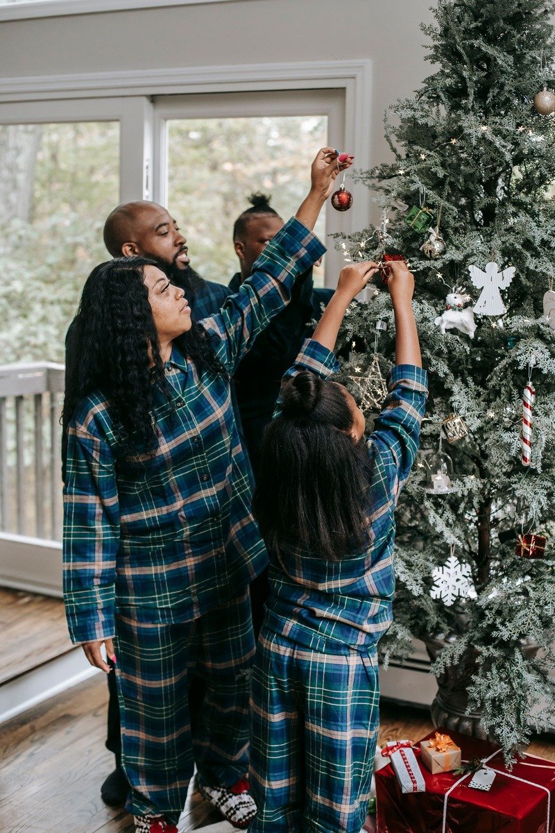 Family in Christmas pajamas posing by the tree at home
