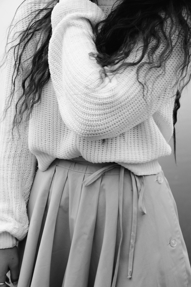 Woman in a pleated skirt and fitted sweater at the office