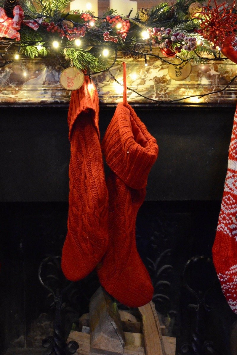 Christmas stockings hanging from a mantel with brass bells