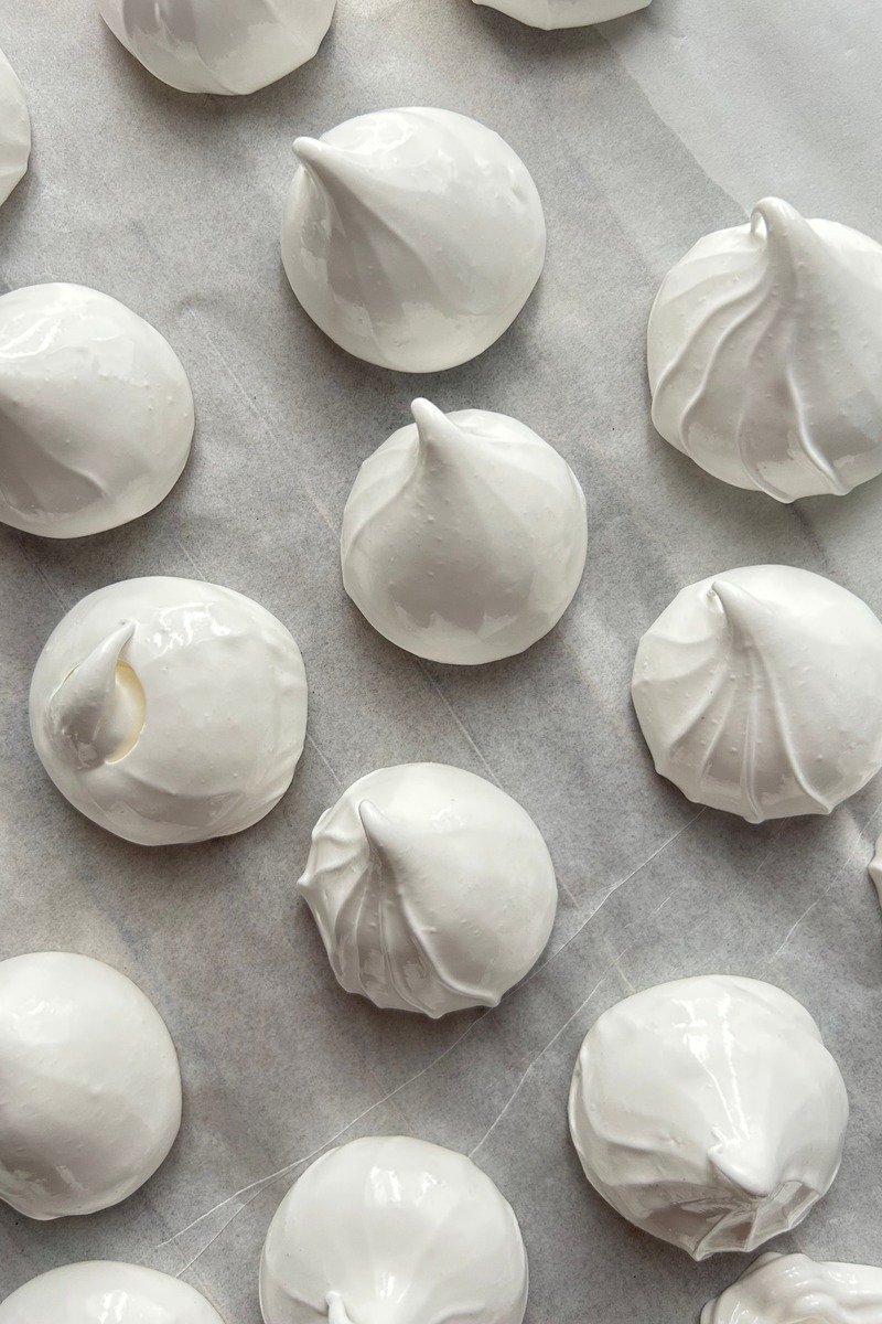 White meringue kisses on a baking tray