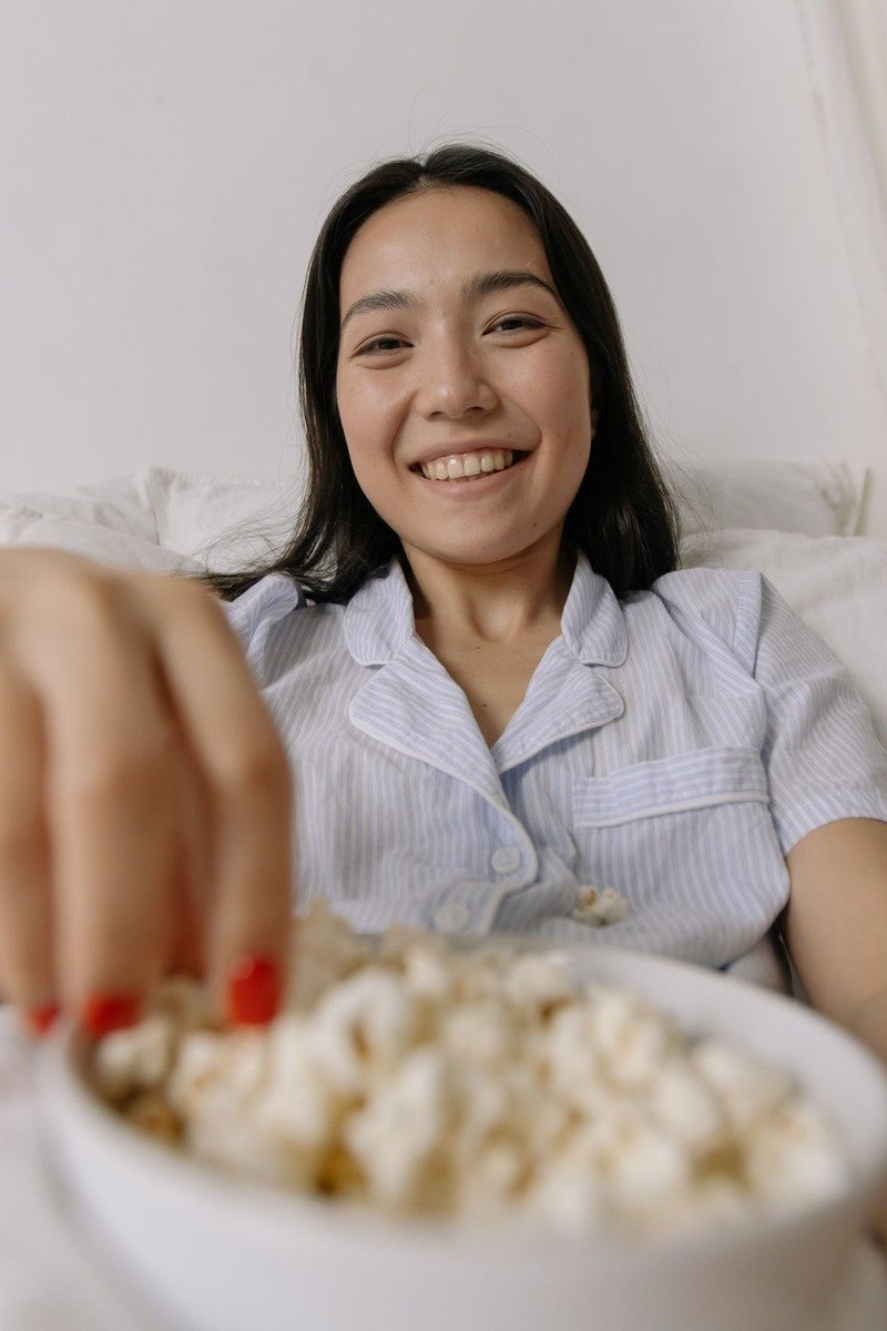 Woman in pajamas with a bowl of popcorn in bed