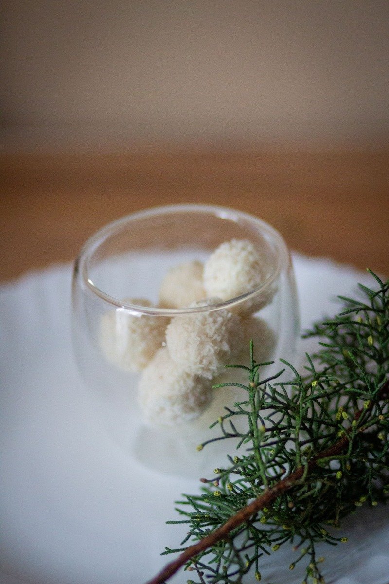 Coconut snowball truffles in a glass cup with greenery