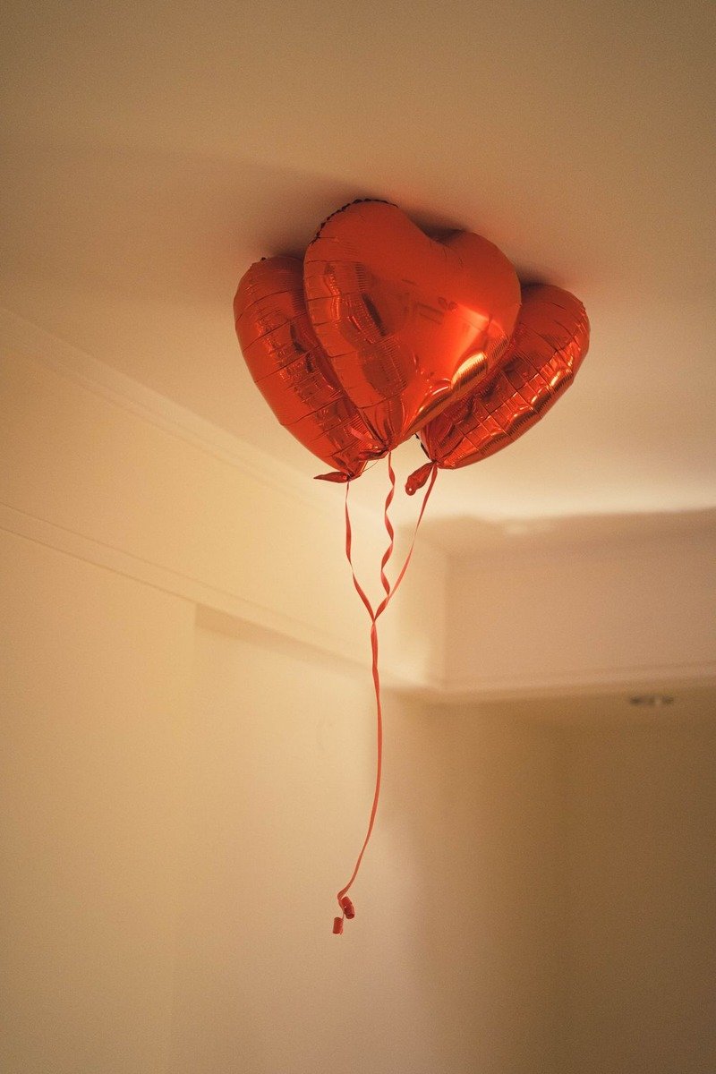 Balloons covering a party room ceiling with ribbon tails