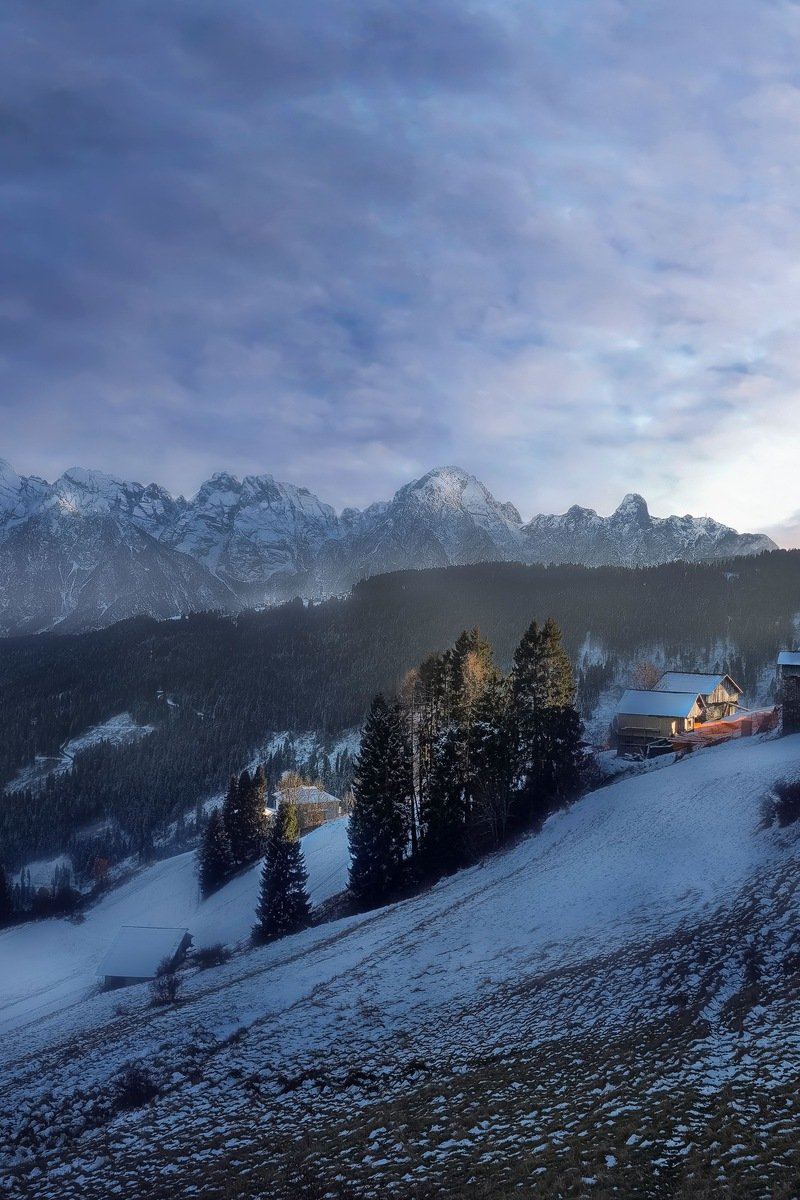 Snowy mountain village at dusk with church tower and jagged alpine peaks