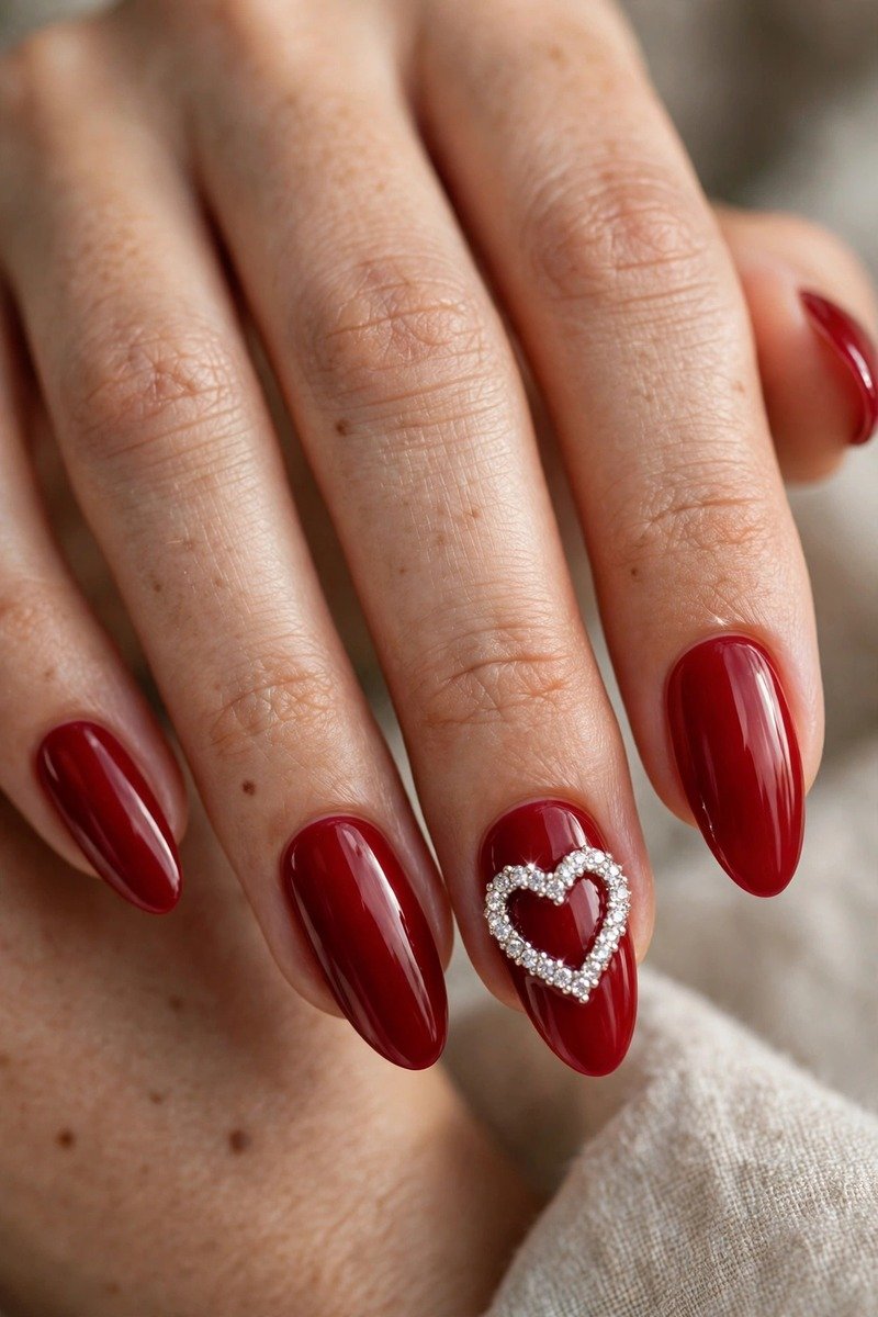 Red nails with a rhinestone heart on the accent nail