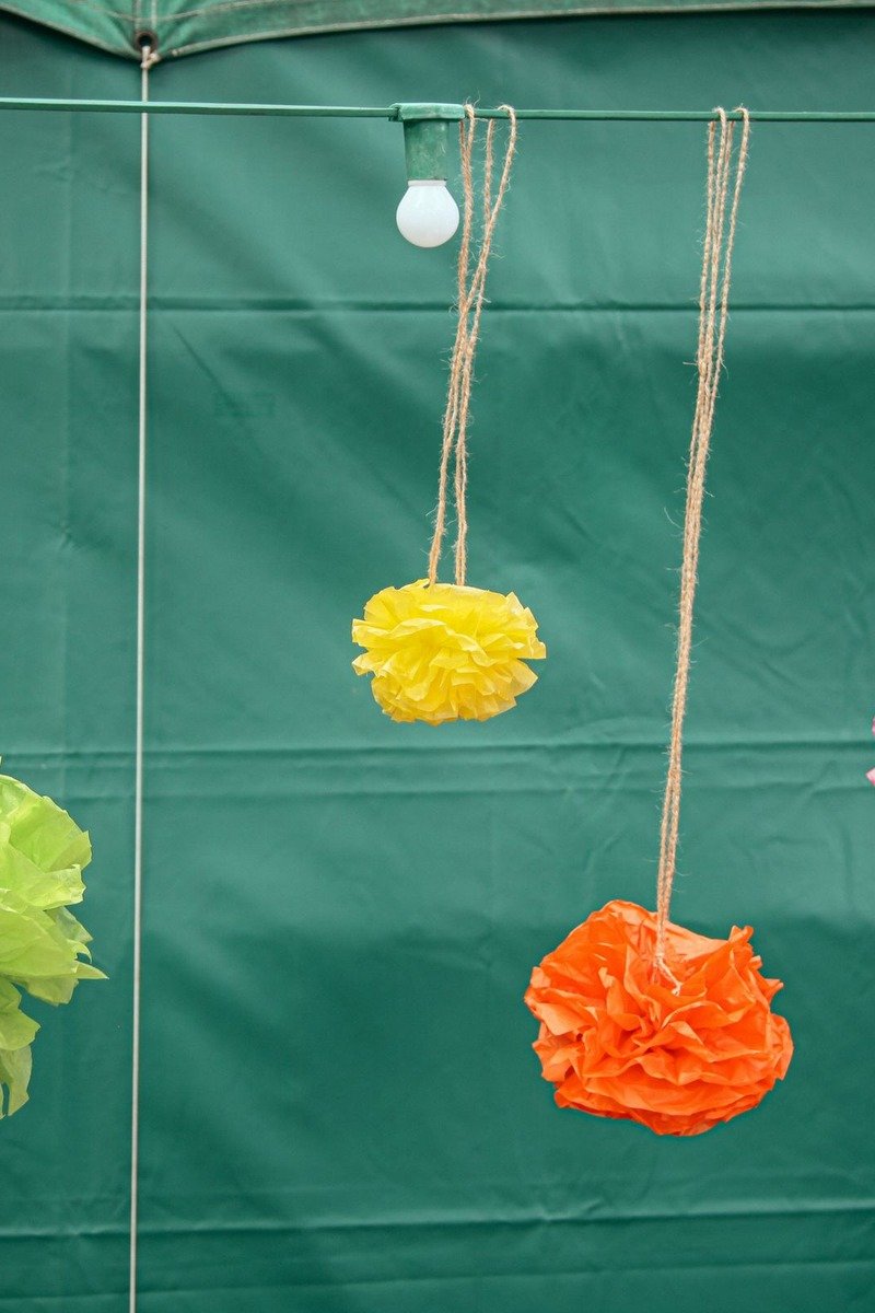 Tissue paper pom poms hanging over a birthday table