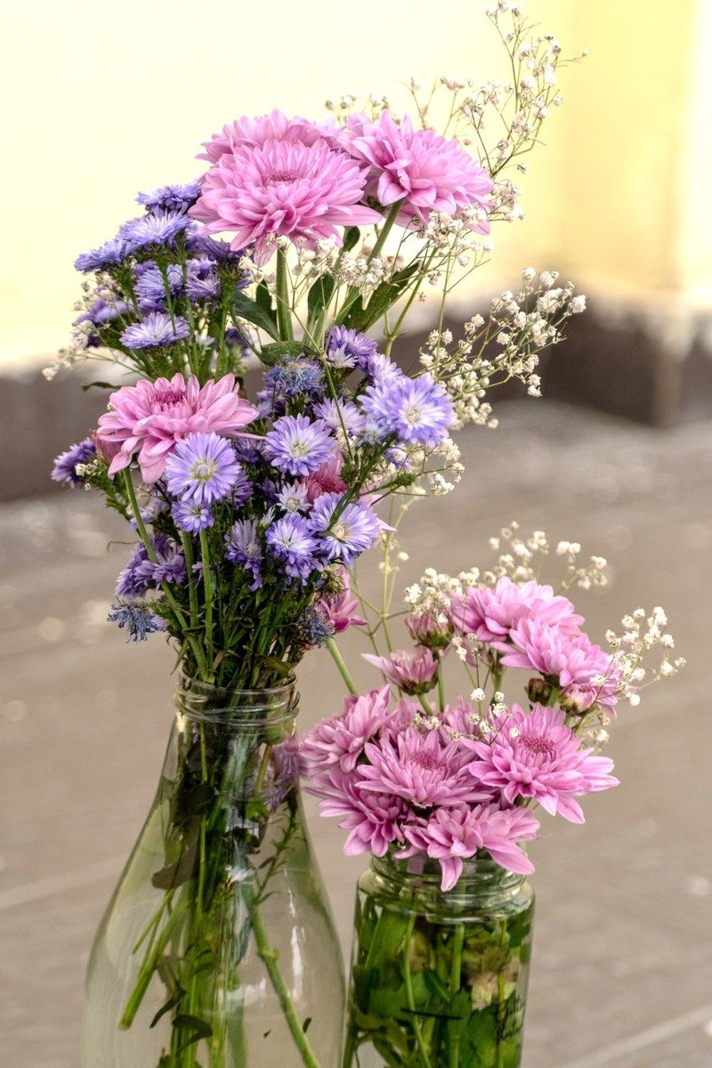 Glass bottles used as flower vases along a birthday table
